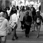 grayscale photography of people walking near buildings