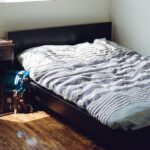 black wooden bed framed and white and gray striped bedspread