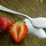 strawberry beside spoon of sugar