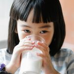 cute asian girl drinking milk from glass