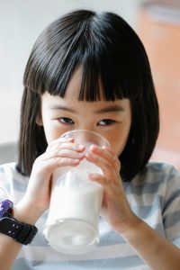 cute asian girl drinking milk from glass
